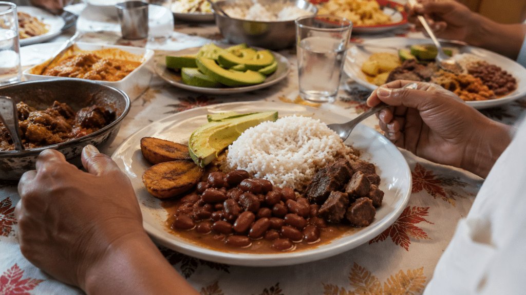 Traditional Dominican family meal with white rice, stewed red beans, seasoned meat, fried green plantains and avocado on a shared dining table