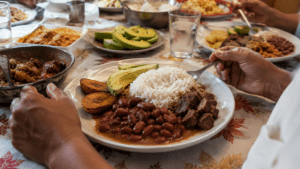 Traditional Dominican family meal with white rice, stewed red beans, seasoned meat, fried green plantains and avocado on a shared dining table