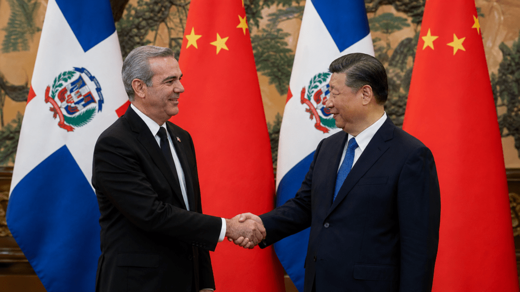 Dominican and Chinese officials shake hands in front of the Dominican and Chinese flags