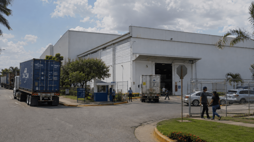 Modern Dominican Republic free trade zone industrial park with workers, freight trucks, shipping containers and an active manufacturing facility