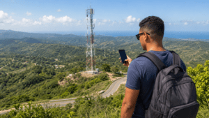 Mobile phone user comparing network coverage in the Dominican Republic with a cell tower in the background