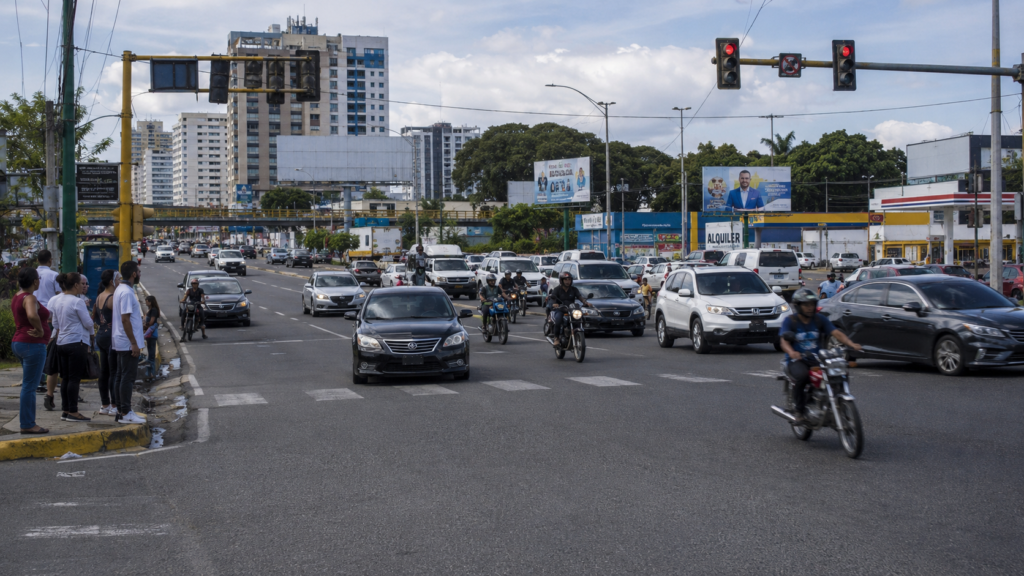 Traffic moves through a busy Santo Domingo intersection as motorists and motorcycles navigate a congested urban roadway