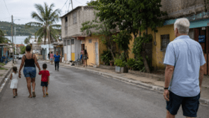 Local Dominican families walking through a modest neighborhood in Sosúa, with an older foreign visitor observing the community from a distance