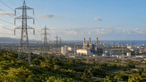 Dominican Republic electricity infrastructure with high-voltage transmission lines, power generation facility and urban areas in the distance