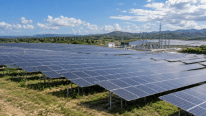 Large solar photovoltaic farm in the Dominican Republic with rows of solar panels, electrical infrastructure and tropical hills